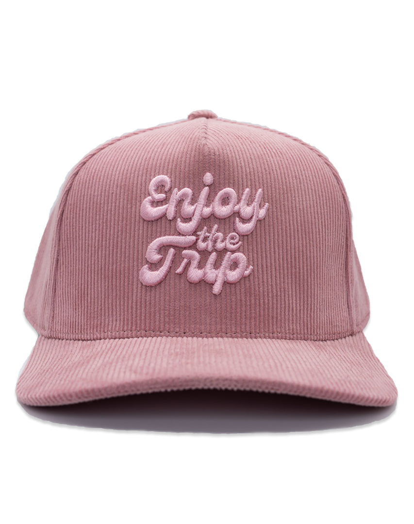 Pink corduroy cap with 'Enjoy the Trip' text on a white background