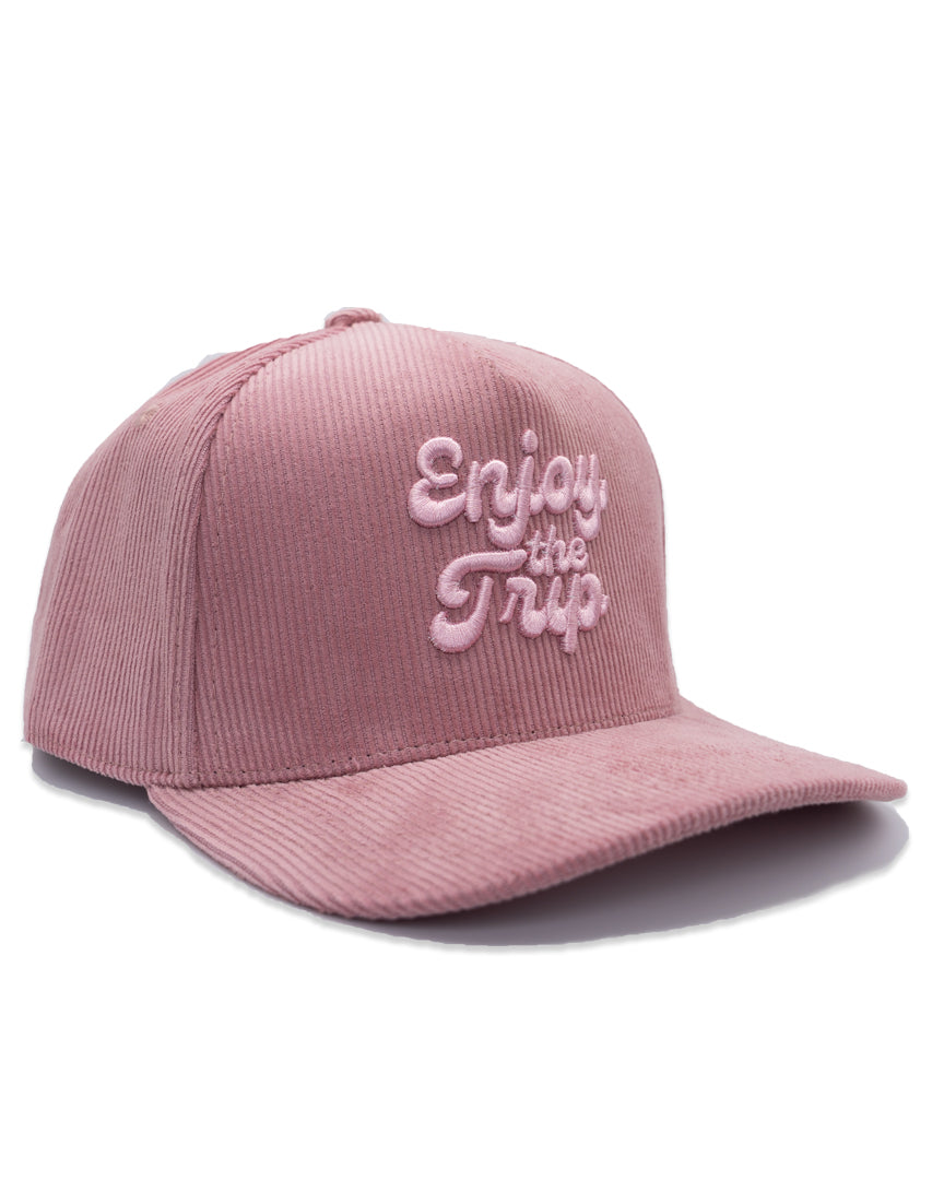 Pink corduroy cap with 'Enjoy the Trip' text on a white background