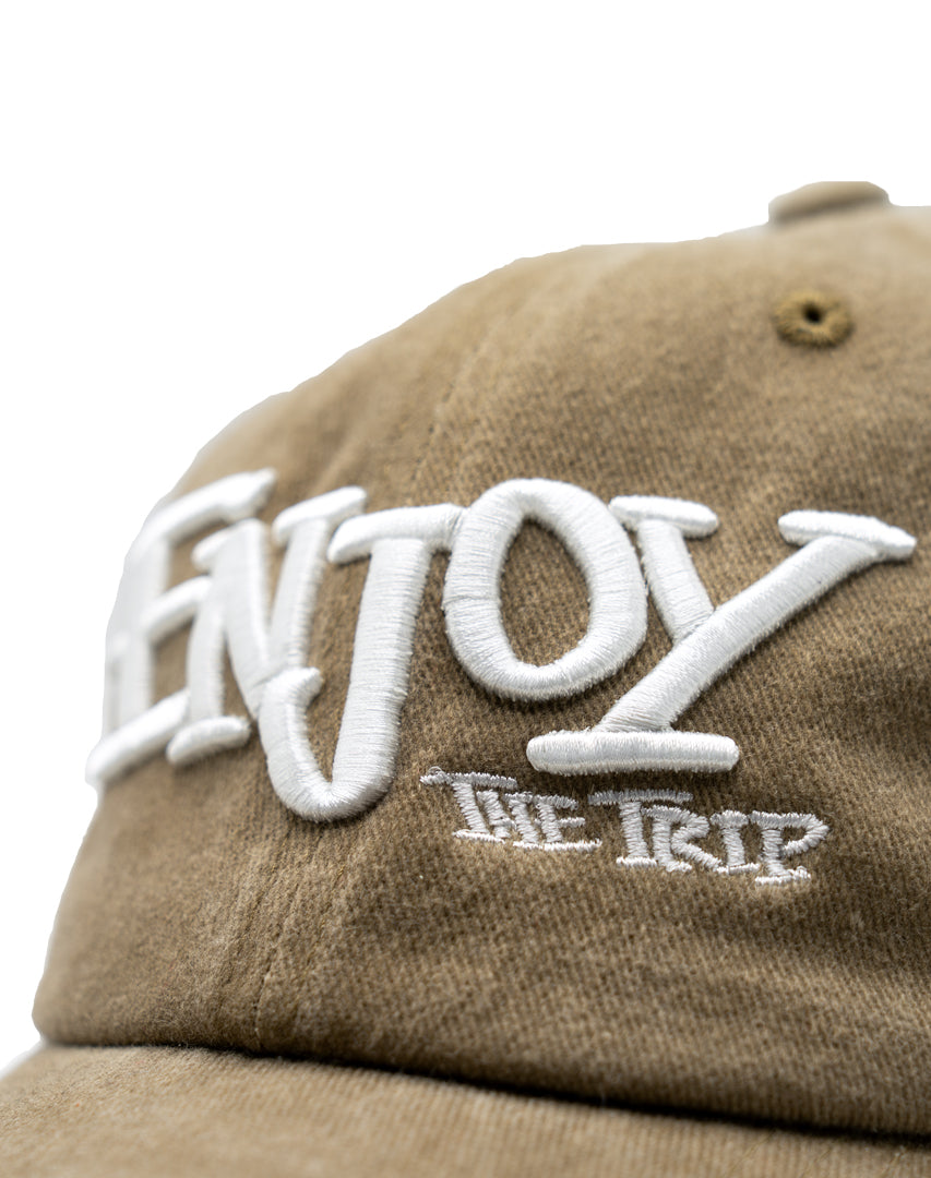 Tan Dad Hat with white embroidery 'ENJOY THE TRIP' on a white background