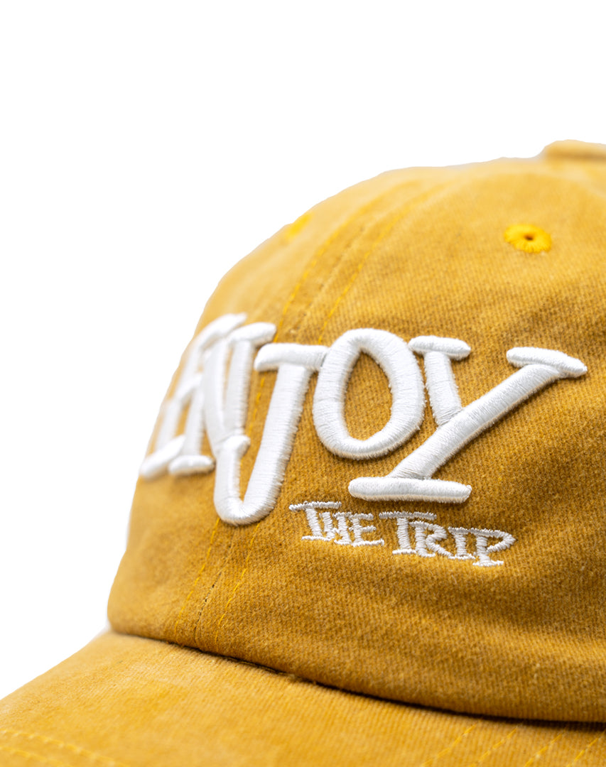 Mustard Washed Cotton Dad Hat with white embroidery 'ENJOY THE TRIP' on a white background