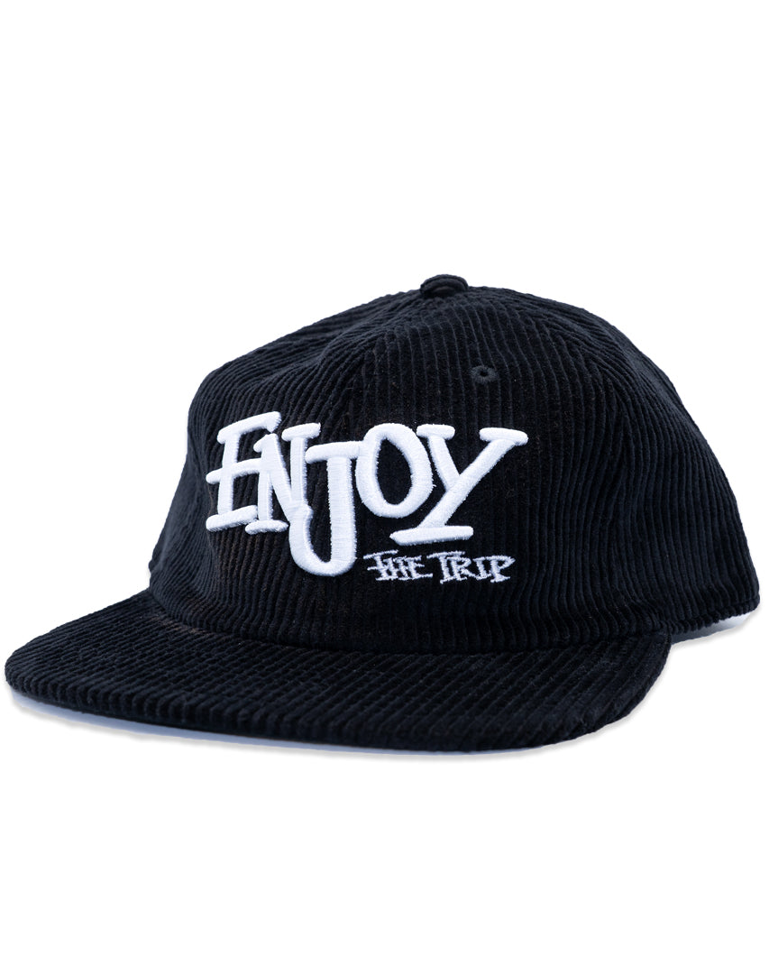 Black corduroy cap with white text 'ENJOY THE TRIP' on a white background