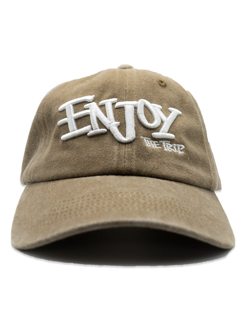 Tan Dad Hat with white embroidery 'ENJOY THE TRIP' on a white background